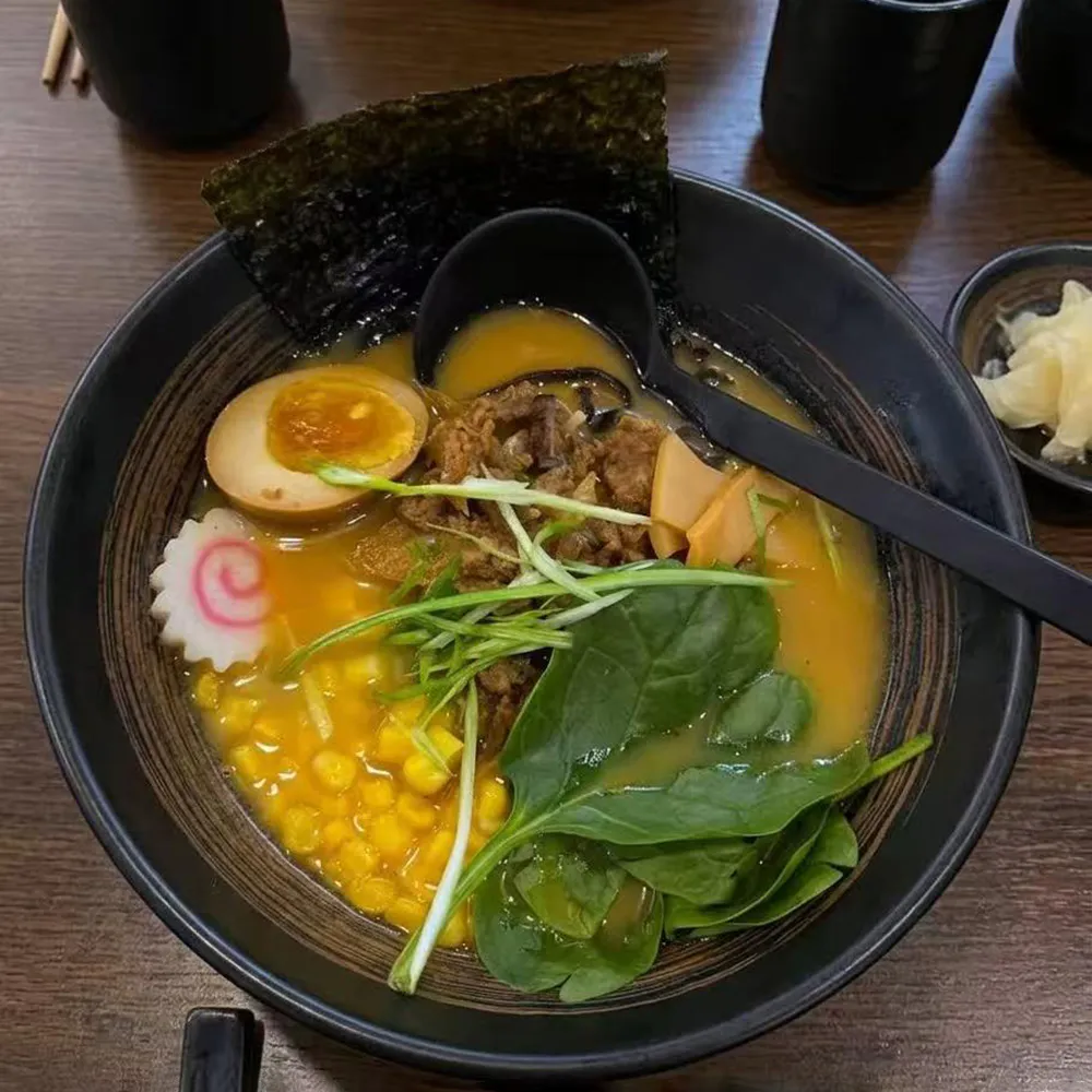 Creamy miso ramen soft boiled egg corn spinach seaweed narutomaki black ceramic bowl at Su's Asian Street Kitchen, an Asian Fusion Restaurant in Westlake